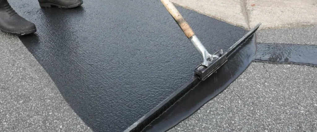 person spreading out sealcoat