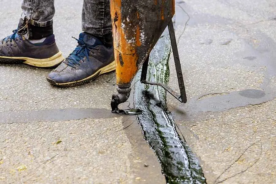 closeup of a person cracksealing pavement