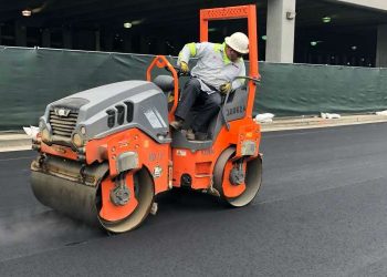 person looking behind him while he is driving an asphalt roller